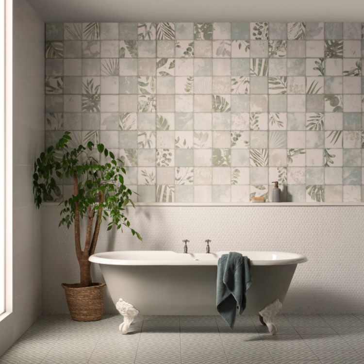 Image of Bathroom with a clawfoot bathtub, botanical-patterned wall tiles, a small plant in a woven pot, and a folded towel hanging over the tub.