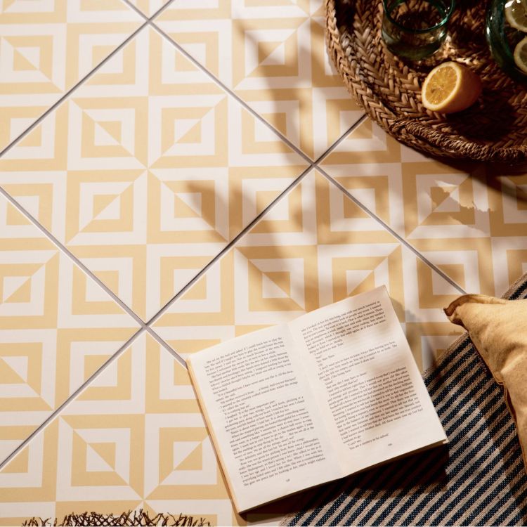 Image of Geometric yellow and white floor tiles with an open book, a woven tray, and a sliced lemon nearby.