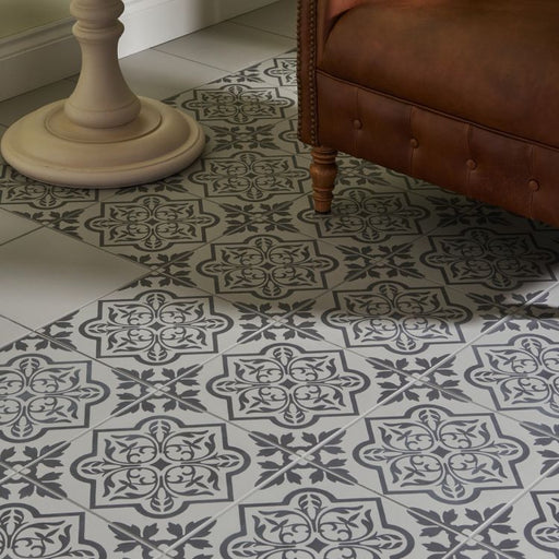 Patterned tile floor with a brown leather chair and white pedestal in a room.