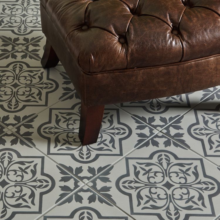 Image of Brown leather ottoman on a patterned tile floor
