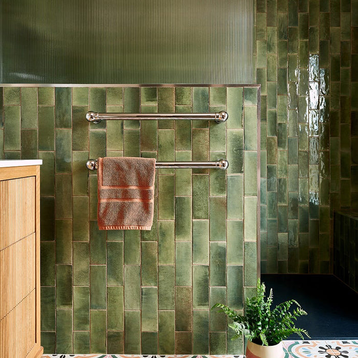 Bathroom with green tiled walls, wooden cabinet, and patterned floor.