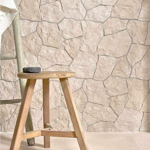 Wooden stool against a stone-patterned wall