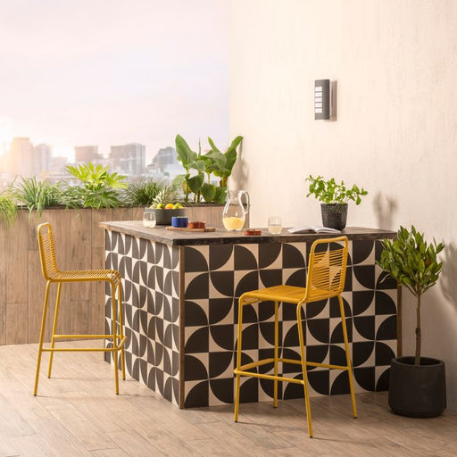 Modern kitchen island with geometric pattern, yellow stools, and cityscape view.