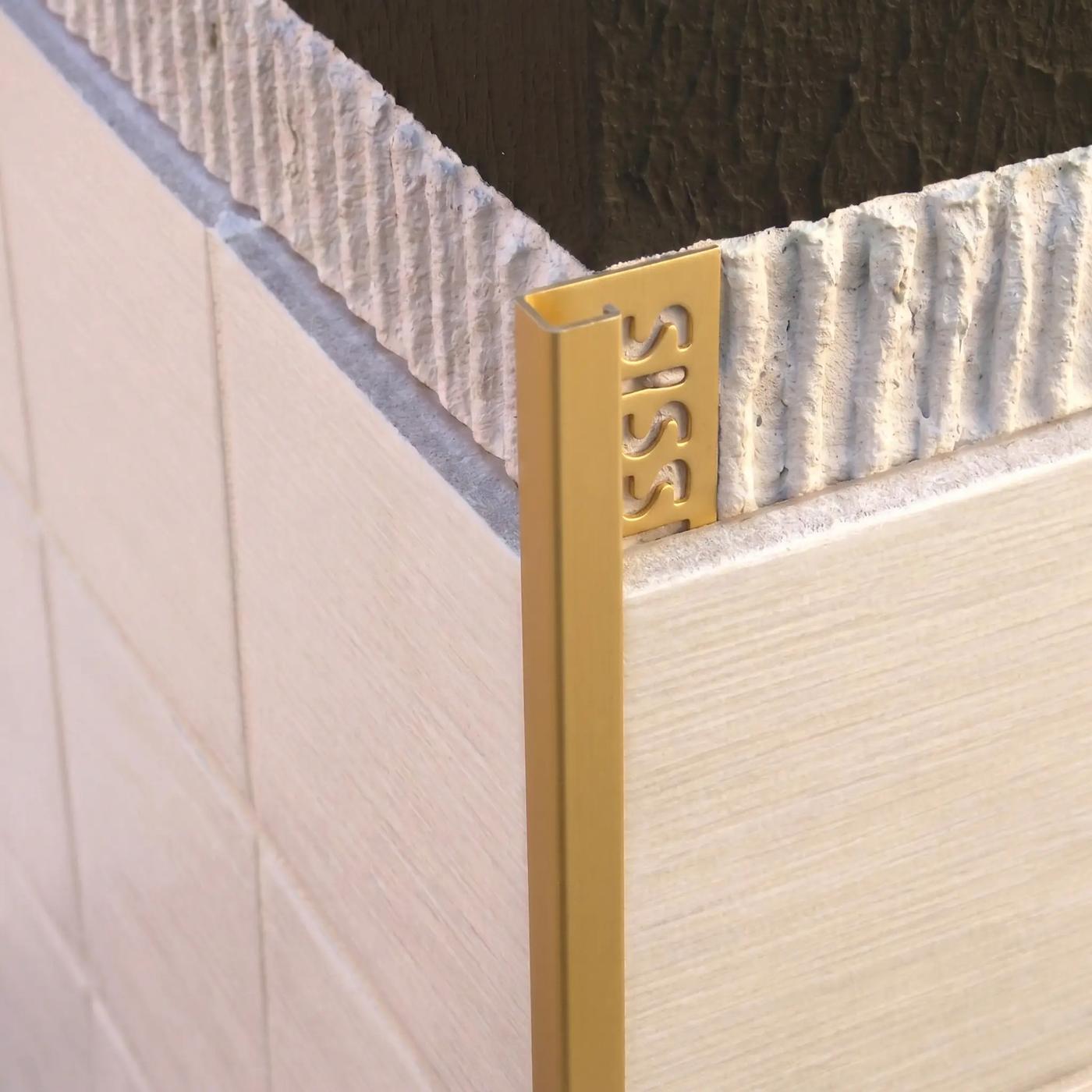 Image of Close-up of a matt gold square edge tile trim fitted to an external corner of cream ceramic wall tiles