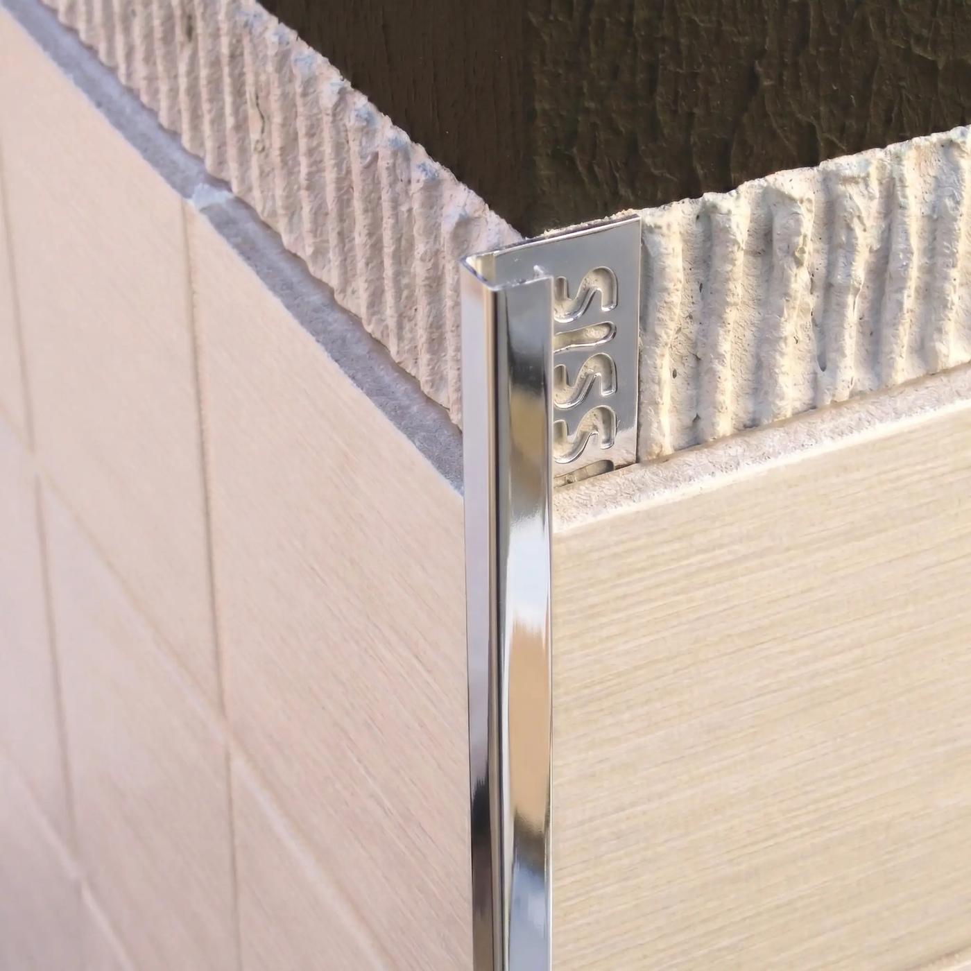 Image of Close-up of a polished silver square edge tile trim fitted to an external corner of cream ceramic wall tiles.