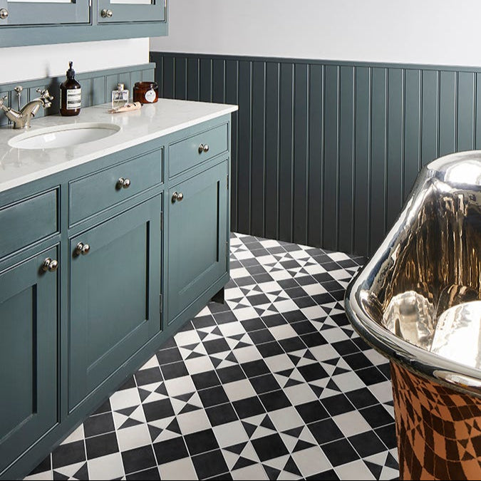Image of Bathroom with teal cabinets, marble countertop, and patterned floor.