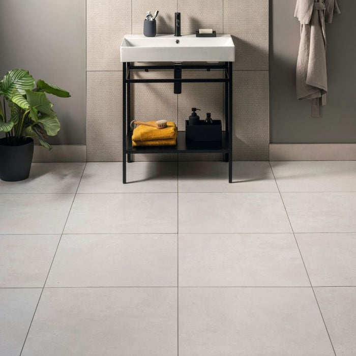 Bathroom with a sink vanity, plant, and towel on a tiled floor.