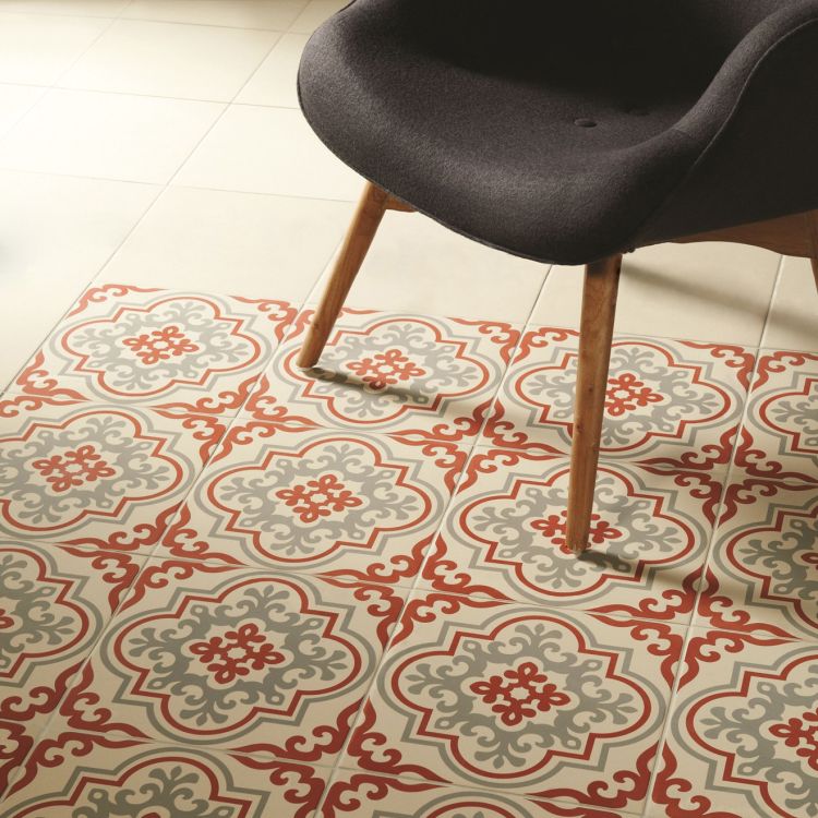 Image of patterned floor tiles in rose, grey, and cream beneath a modern dark chair with wooden legs