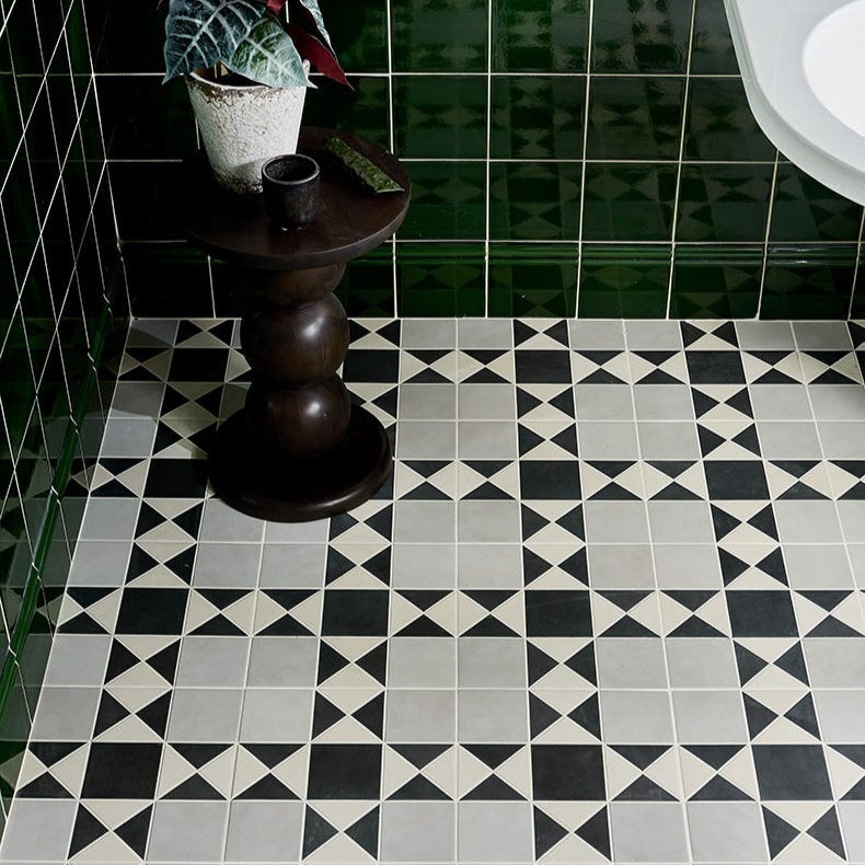 Image of Bathroom with black and white geometric tile floor, wooden pedestal, and green tiled walls.