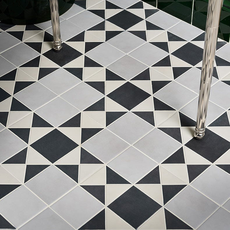 Image of Geometric tile pattern on a floor with black, white, and gray tiles.